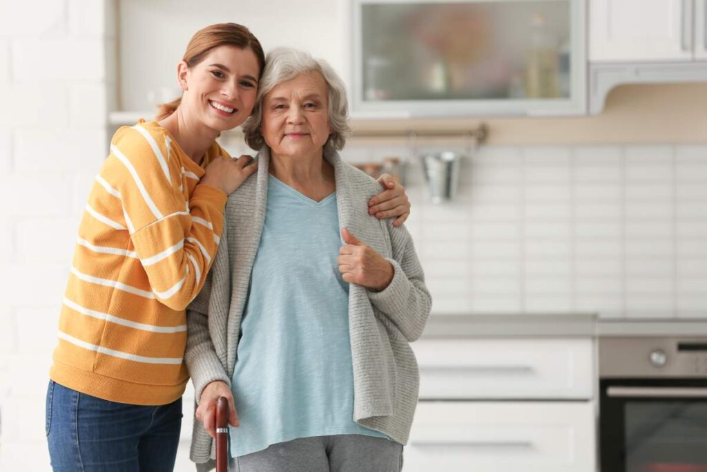 A caregiver and an older adult sitting at a kitchen table discussing paperwork with a family member.