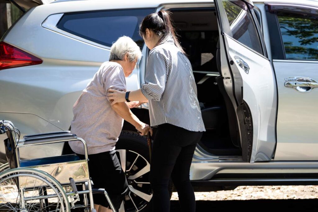 Adult daughter supporting her elderly mother with dementia at a kitchen table, both engaged in conversation.