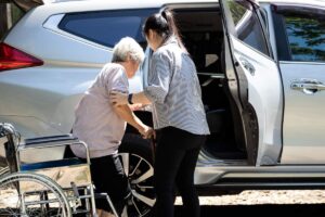 Adult daughter supporting her elderly mother with dementia at a kitchen table, both engaged in conversation.