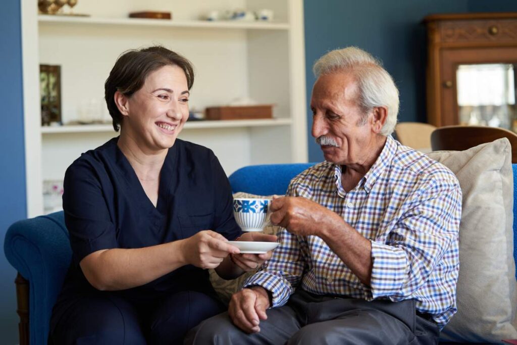 Two older adults following a gentle exercise routine together in a bright living room.